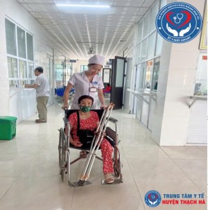 Viên chức y tế tận tình đẩy xe lăn đưa người bệnh cao tuổi đến phòng khám